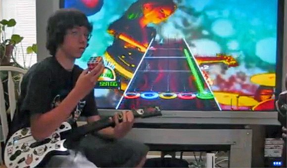 Uber-nerd gioca a Guitar Hero mentre risolve due cubi di Rubik (!)