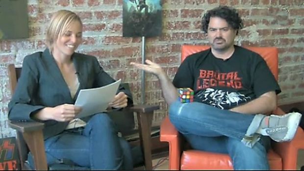 Tim Schafer risolve un cubo di Rubik mentre una ragazza legge  la colonna sonora di Brutal Legend
