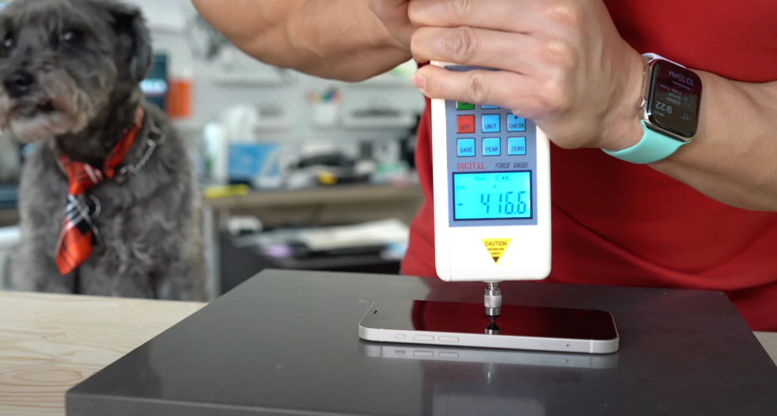 Un tecnico misura la resistenza del display di iPhone 12 con uno strumento apposito. Oltre quel punto, si romperà.