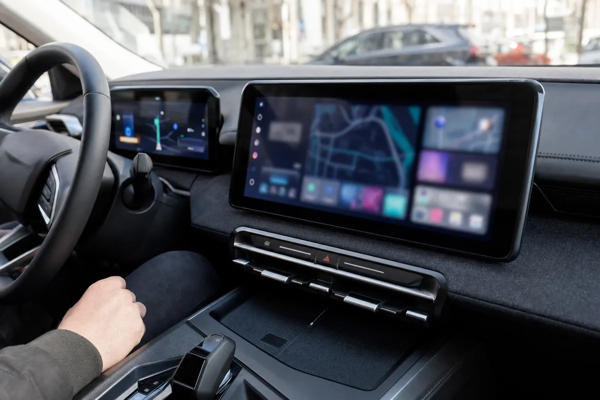 Interno di auto moderna con grande display infotainment e quadro strumenti digitale con interfaccia di navigazione sfocata