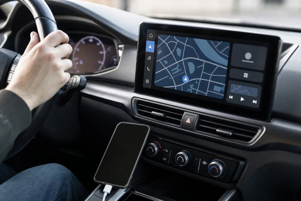 Schermo infotainment con mappa di navigazione e smartphone collegato nella console di un’auto moderna