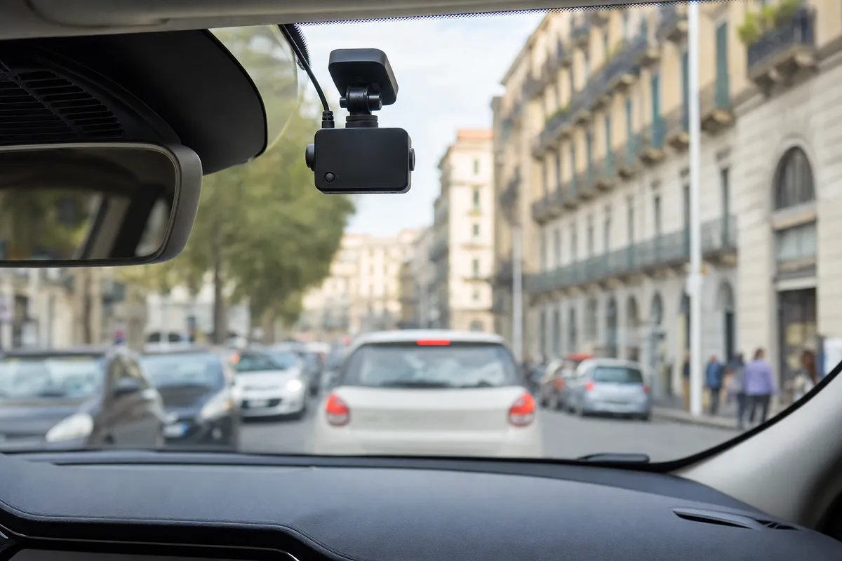 Dash cam montata dietro lo specchietto retrovisore con strada urbana trafficata sullo sfondo sfocato
