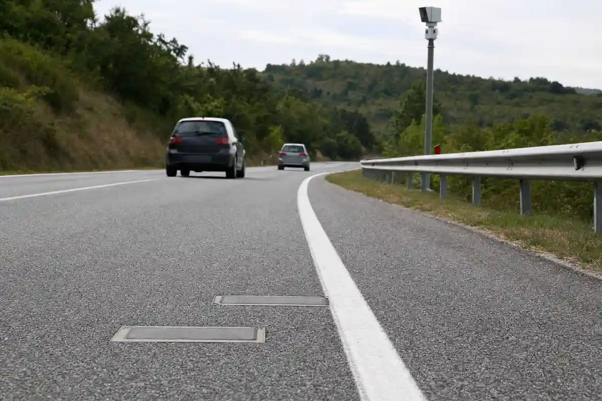 Strada extraurbana a due corsie con sensori nell’asfalto e telecamera di monitoraggio, due auto in lontananza