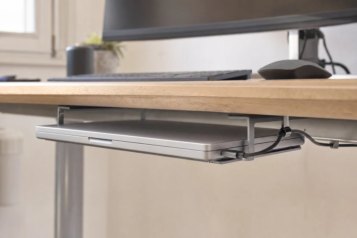 Portatile in alluminio chiuso montato sotto una scrivania in legno con staffe metalliche e cavo laterale