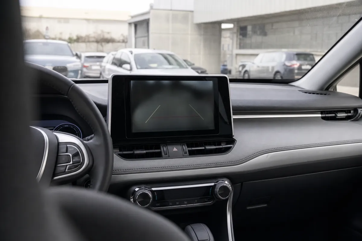 Schermo centrale di un SUV con immagine della retrocamera scura e linee di parcheggio, visto dall’abitacolo